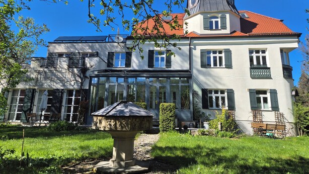 A two-story building with a red-tiled roof, large windows, and a conservatory. - Garden Villa Schwanstein I Apartment "Lohengrin" (Füssen)