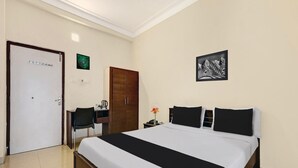 A hotel room with a bed, a desk, a chair, a wardrobe, and a framed picture on the wall. - Super OYO Collection O Jagadamba Junction Near Beach Road (Visakhapatnam)