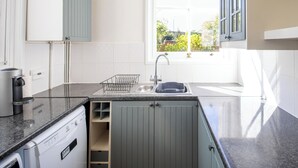 Cocina moderna con lavavajillas, un lavabo y una ventana con vistas a zonas verdes.