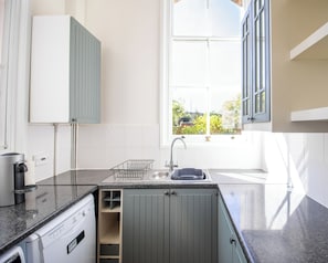 A modern kitchen with a dishwasher, a sink, and a window with a view of greenery. - 3 Bed Home in Shrewsbury (Shropshire)