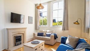 Una sala de estar con chimenea, un sofá, una mesa de centro y una televisión.