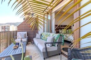 Ein Balkon mit einer Couch, einem kleinen Tisch und einem Blumentopf.