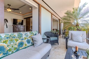 Ein modernes Wohnzimmer mit einer Couch, Sesseln, einem Esstisch und einem Deckenventilator.