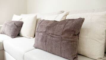 A white sofa with several cushions, including a ribbed one and a plain one.