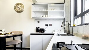 A modern kitchen with a white countertop, a black stove, a sink, and a window. - Neptune Residency (Nairobi)