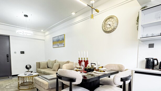 A modern living room with a dining table, sofas, and a kitchen area. - Neptune Residency (Nairobi)