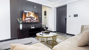 A modern living room with a flat-screen TV, a fireplace, a round coffee table, and a sofa. - Neptune Residency (Nairobi)