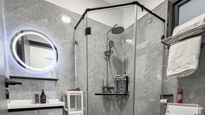 A modern bathroom with a glass-enclosed shower, a toilet, a sink with a mirror, and a towel rack. - Neptune Residency (Nairobi)