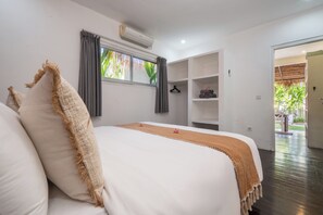 A bedroom with a bed, a window with curtains, an air conditioning unit, and a view of the outdoors. - Maison 246 2BR Cozy Private Pool Villa In Vibrant Canggu (Badung)