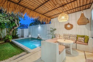 A poolside area with a thatched roof, a lounge with cushions, and a hanging light fixture. - Maison 246 2BR Cozy Private Pool Villa In Vibrant Canggu (Badung)