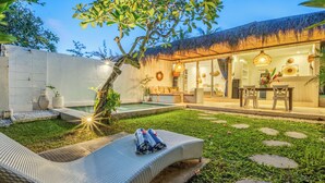 Eine Poollounge mit Korbsessel, kleinem Pool und Essbereich mit Tisch und Stühlen.
