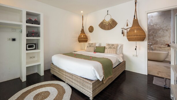 Ein Schlafzimmer mit einem großen Bett, einem Einbauschrank, einer Pendelleuchte und einem Badezimmer mit einer Badewanne.