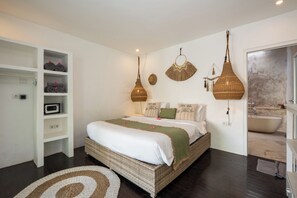 A bedroom with a large bed, a built-in wardrobe, a hanging light fixture, and a bathroom with a bathtub. - Maison 246 2BR Cozy Private Pool Villa In Vibrant Canggu (Badung)
