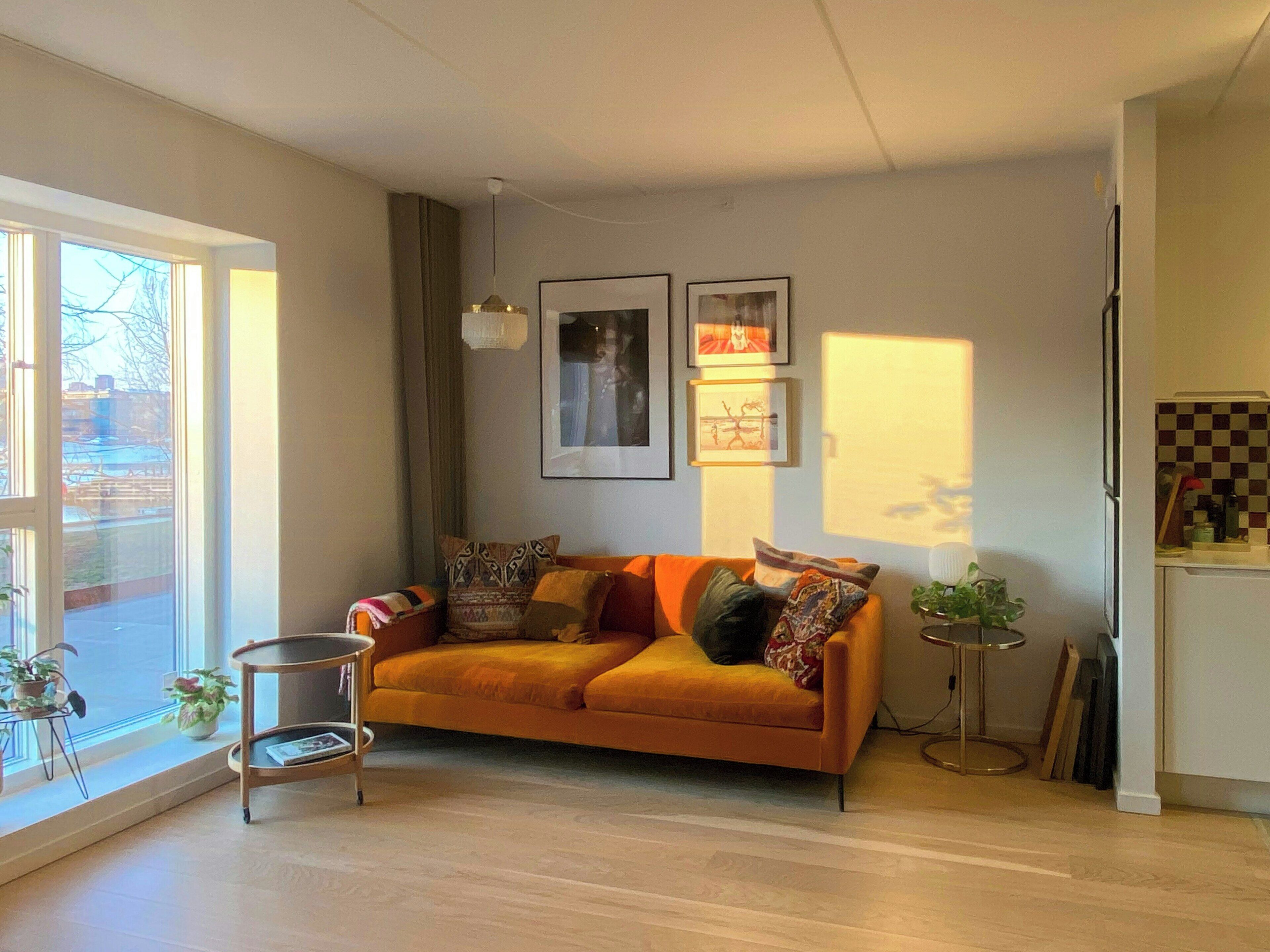 A living room with a sofa, a small side table, a floor lamp, and a view of the outside.