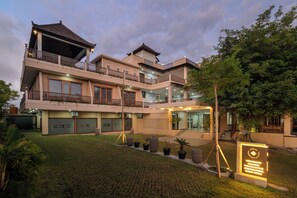 A multi-story building with a traditional architectural style, featuring balconies, a courtyard, and potted plants. - Sembari Coliving Ubud (Gianyar)