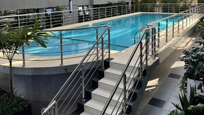A swimming pool with steps leading down to it, surrounded by a building with large windows and balconies. - Neptune Residency (Nairobi)