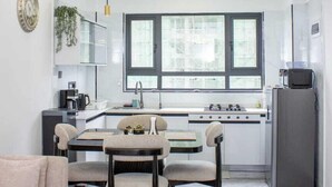 A modern kitchen with a dining area, a sofa, and a large window. - Neptune Residency (Nairobi)