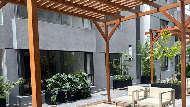 An outdoor patio with wooden pergola, seating, and potted plants. - Neptune Residency (Nairobi)