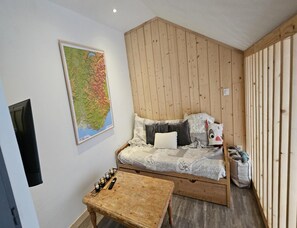 Um quarto aconchegante com uma cama, um mapa na parede, uma mesinha e paredes de madeira.