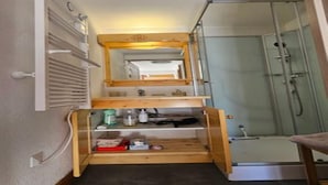 A narrow hallway with a shower, a mirror, and a shelf with toiletries. - Alpine Retreat With Balcony and Parking (Saint-Sorlin-d'Arves)