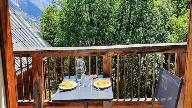 A wooden deck with a table set for two, a pitcher, and plates of food. - Alpine Retreat With Balcony and Parking (Saint-Sorlin-d'Arves)