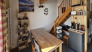 A compact kitchen with a wooden table, a built-in stove, and a staircase. - Alpine Retreat With Balcony and Parking (Saint-Sorlin-d'Arves)