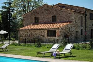 A stone building with a tiled roof, a swimming pool, and two lounge chairs. - Flat at farm stay with spa and pool (Massa Marittima)