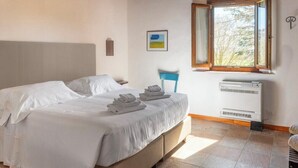 Ein Schlafzimmer mit einem Bett, einem Sessel, einem Fenster und einer Klimaanlage.