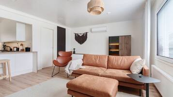 A modern living room with a sofa, ottoman, and a small table.