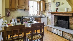 Eine Küche mit Holzausstattung, einem Esstisch mit Stühlen, einem eingebauten Backofen und einer Steinwand.