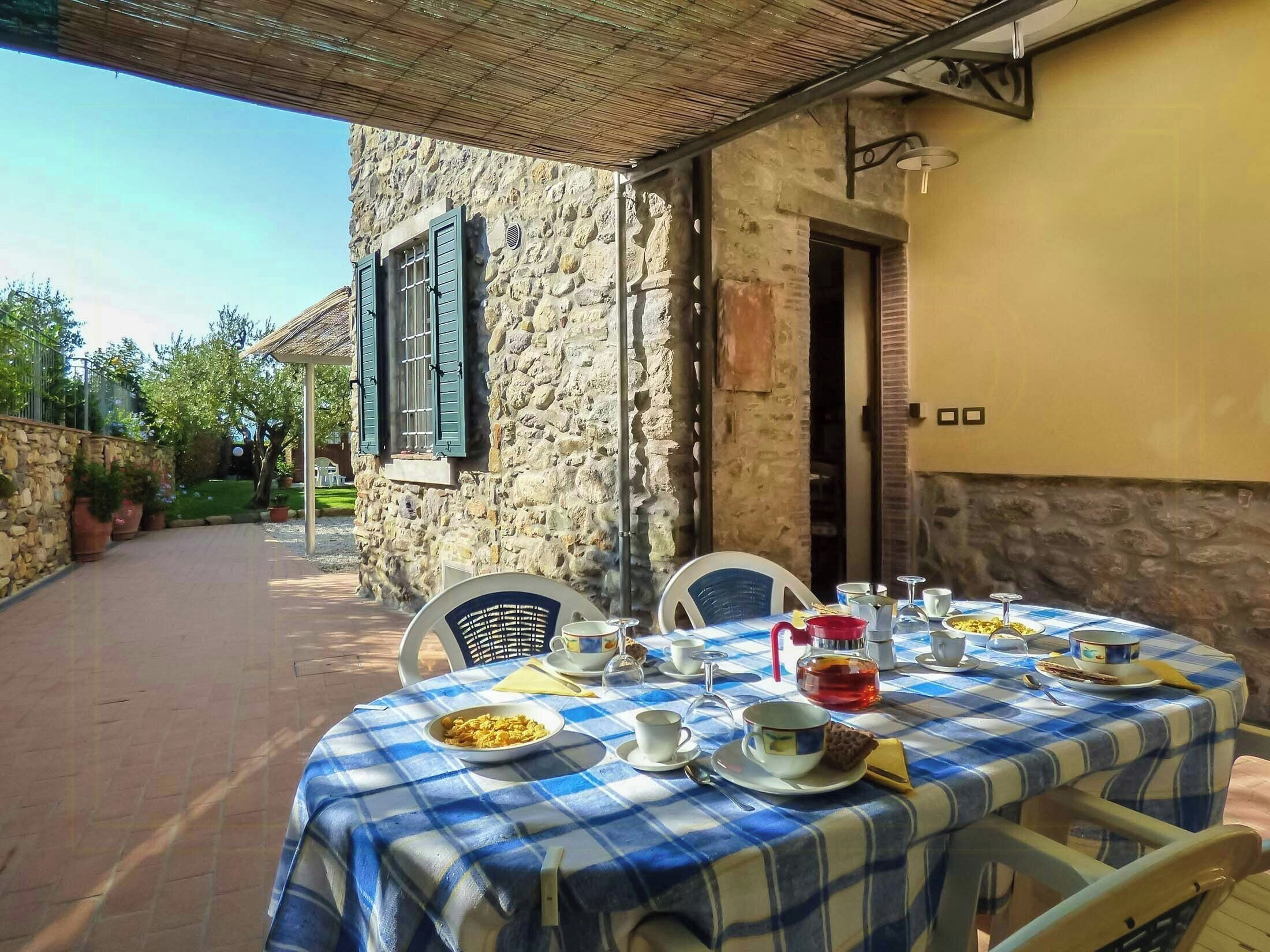 A stone building with a dining table set for two, covered with a blue and white checkered tablecloth.