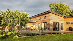 Una casa moderna con una terraza, un árbol y un patio.