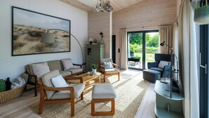 Una sala de estar moderna con un cuadro grande, muebles de madera y vistas a través de la puerta de vidrio.