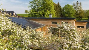 Una casa moderna con paneles solares, fachada de madera y jardín con flores floreciendo.