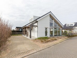 A modern two-story house with a sloped roof, large windows, and a paved driveway. - DuinZilver A by Interhome (Renesse)