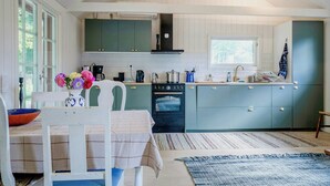 Una cuina moderna amb armaris verds, una zona de dinar amb taula i cadires, i un gran finestral que aporta llum natural.