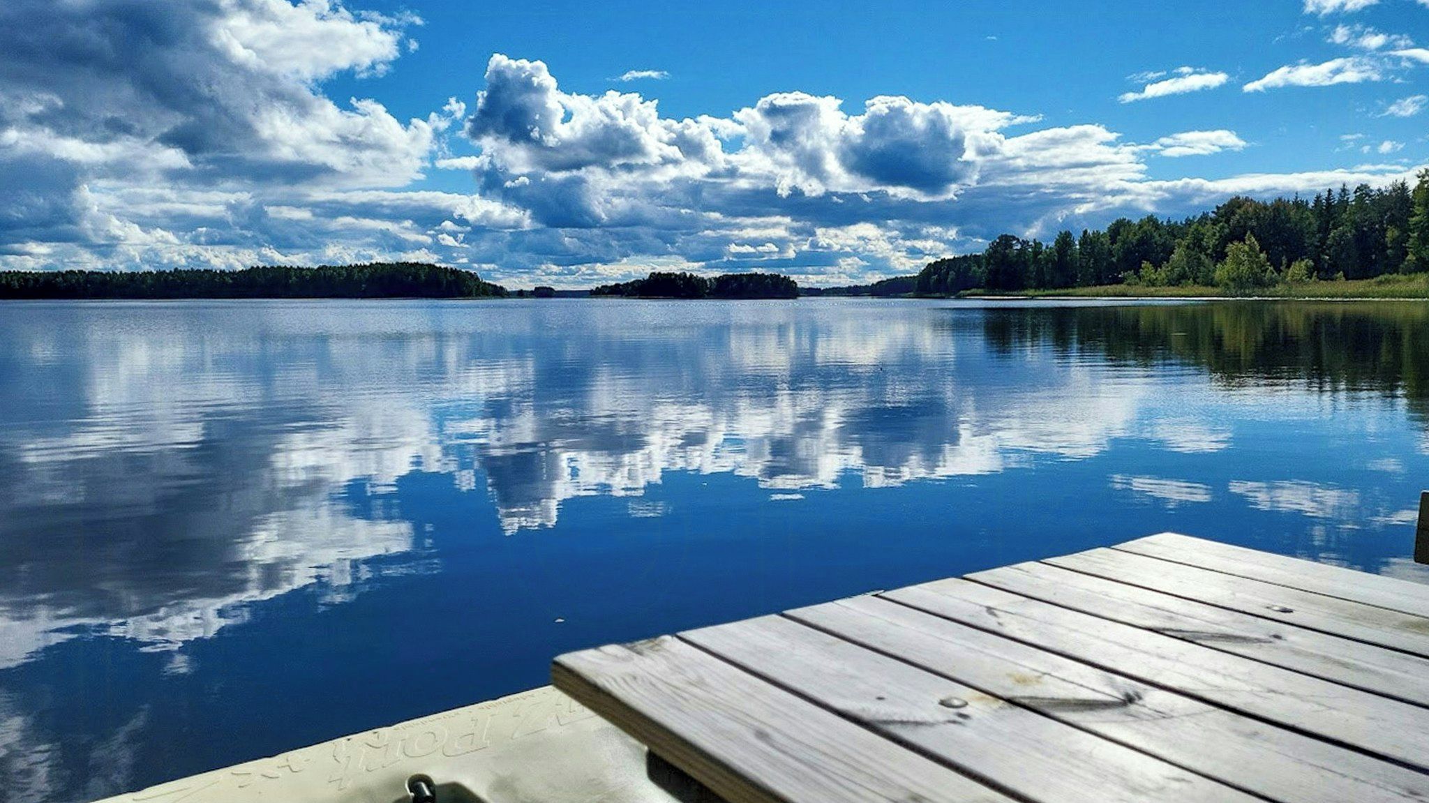 Un lac paisible, avec une jetée en bois qui s’avance sur l’eau.