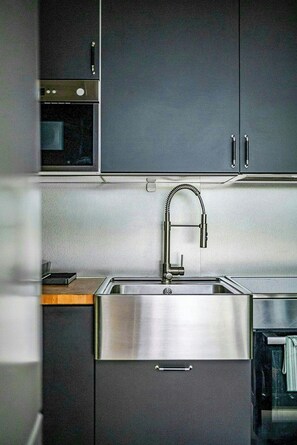 Una cocina moderna con electrodomésticos de acero inoxidable, horno integrado y un solo grifo.