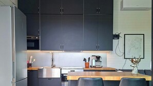 A modern kitchen with dark cabinets, stainless steel appliances, and a wooden island with bar stools. - Cottage with lake view and boat at Lake Storsjön (Sandviken)