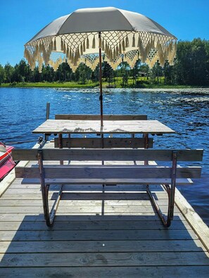 Puinen laituri, jossa on piknikpöytä ja riippuva aurinkovarjo.