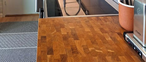 Una cocina moderna con pileta de acero inoxidable, alacenas oscuras y encimera de madera.