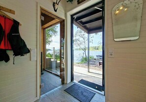 A doorway leading to an outdoor area with a view of a body of water and trees. - Cottage with lake view and boat at Lake Storsjön (Sandviken)