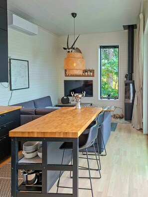 A modern living room with a wooden dining table, grey sofa, and a fireplace.