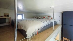 A single bed with a white and red floral bedspread, a bedside table with a lamp, and a wardrobe. - Cottage with lake view and boat at Lake Storsjön (Sandviken)