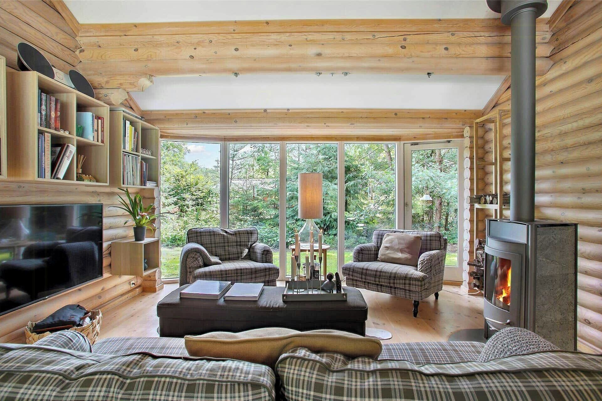 A cozy cabin interior with a fireplace, plaid furniture, and a bookshelf.