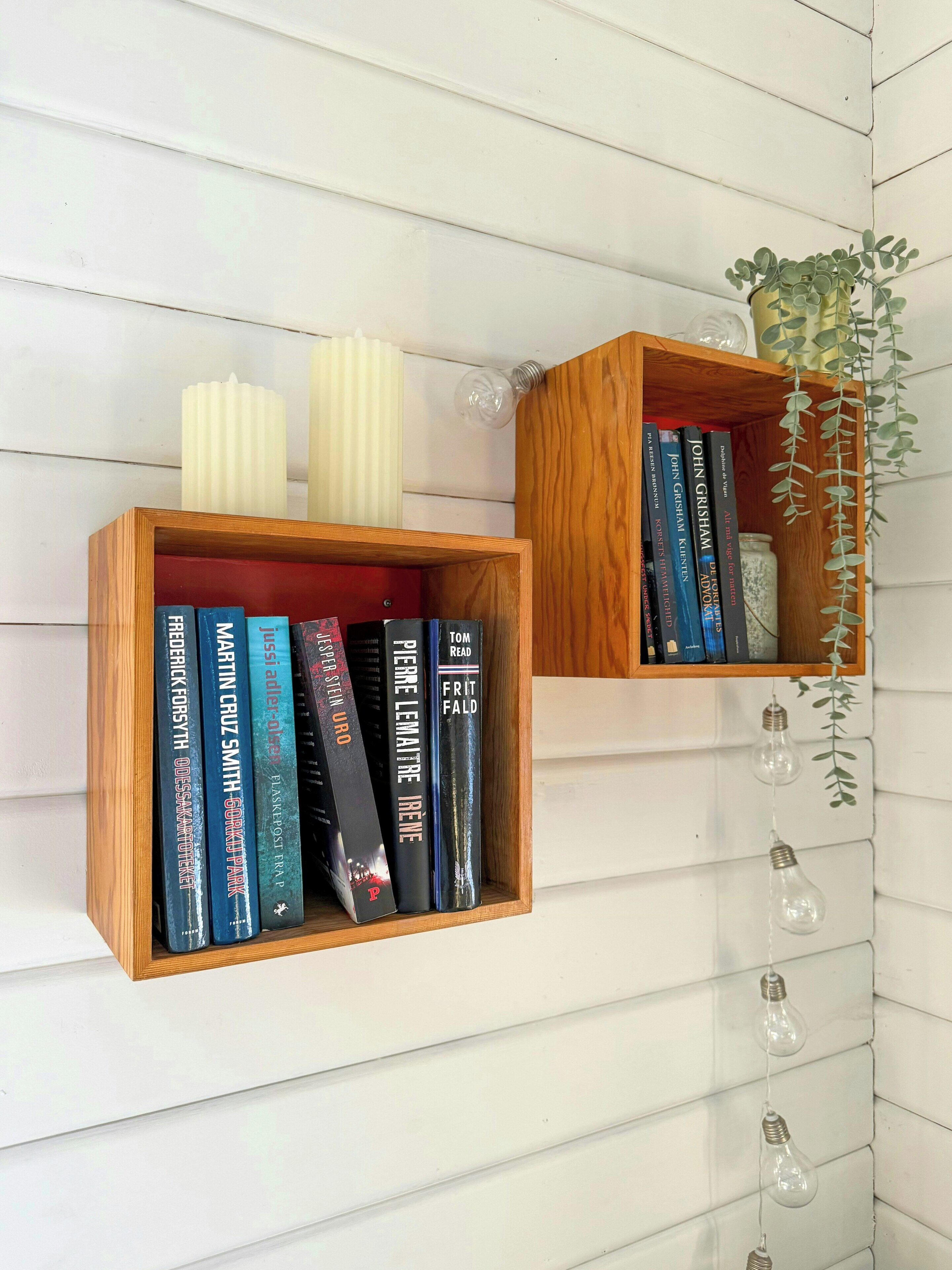 Zwei Bücherregale aus Holz an einer weißen Wand, jedes gefüllt mit Büchern und Dekorationselementen.