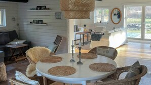 Un coin repas avec une table ronde, des chaises en osier et un luminaire suspendu.