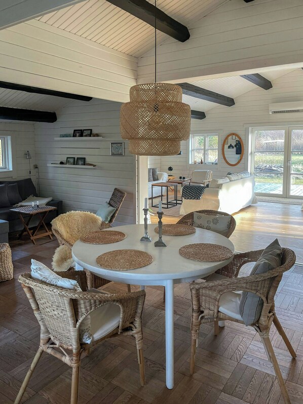 Uma sala de jantar com uma mesa redonda, cadeiras de vime e um lustre.