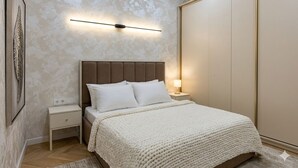 A bedroom with a bed, nightstand, wall-mounted light, and wardrobe. - Modern Apartment in Alfraganus  Rent Car & Moto (Tashkent)