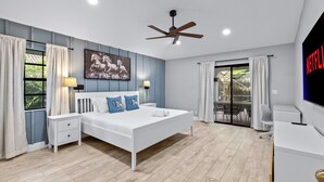 A modern bedroom with a bed, nightstands, a ceiling fan, and a TV. - Screened Pool + Firepit + Outdoor Lounge | Mins to WEF + Polo | Palm & Pool (Wellington)